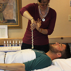 Practitioner working with a Gemstone Therapy client with gems wrapped on wand