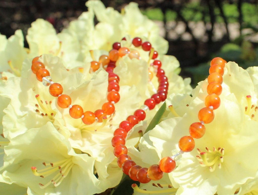Orange Carnelian necklace draped on white flowers