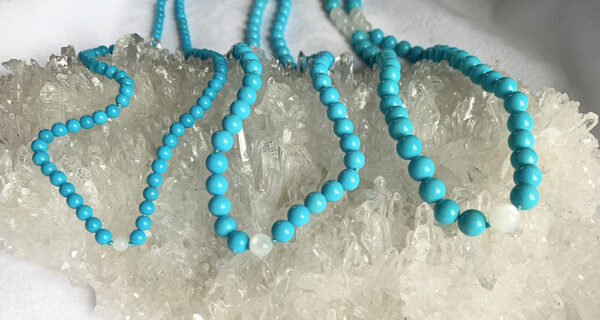 three turquoise healing gemstone necklaces on quartz crystal