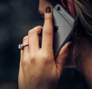 Woman holding phone with Diamond ring on her hand