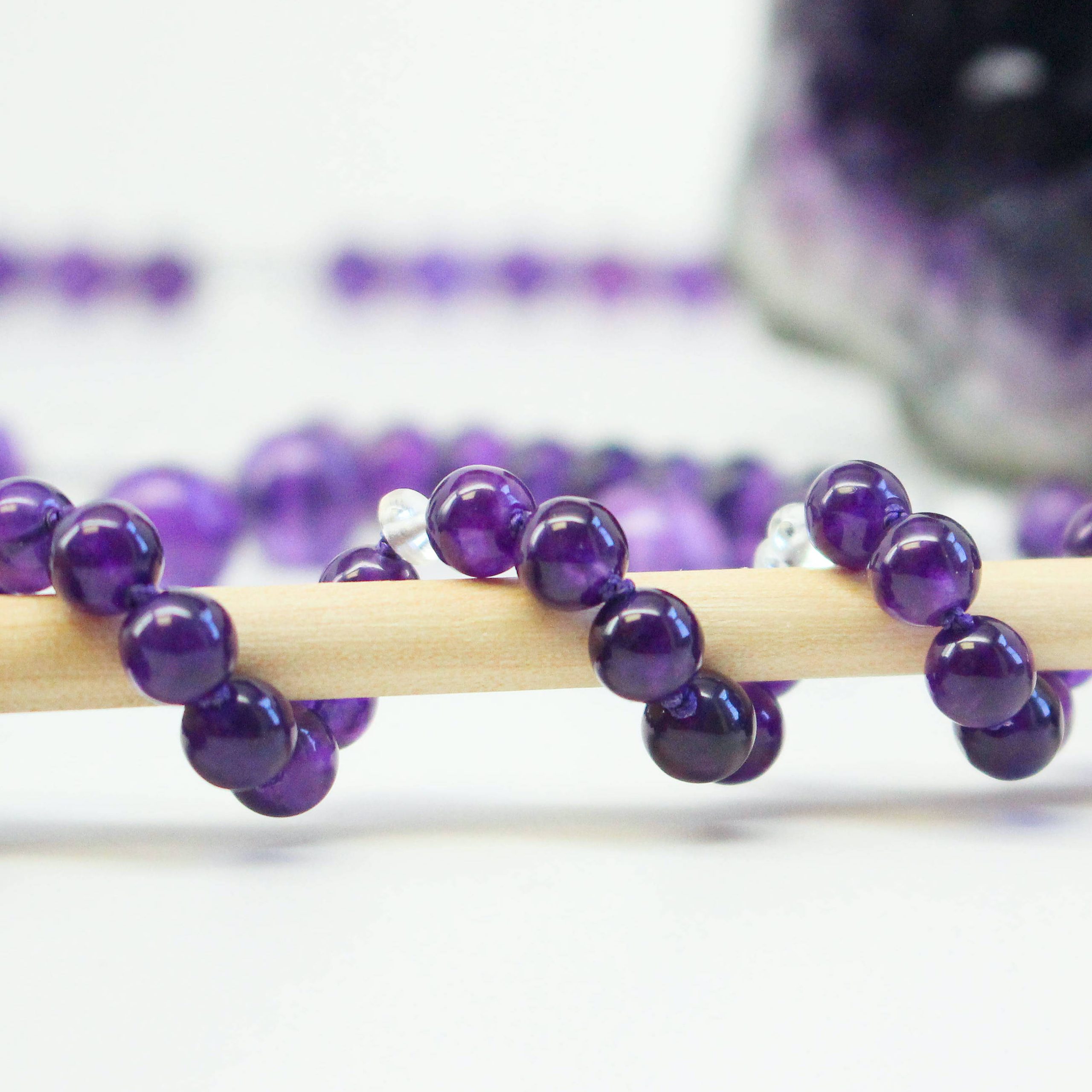 Amethyst gemstone necklace wrapped around therapy wand for Gemstone Therapy