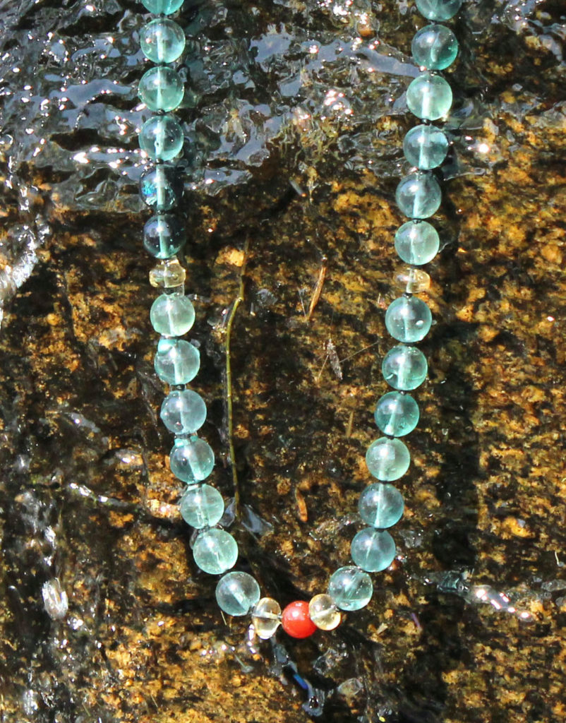 Blue-Green Fluorite Living River necklace on rock