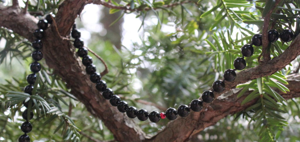 Onyx gemstone necklace draped over two tree branches