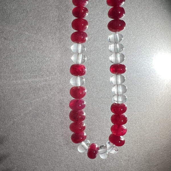 Ruby and White Beryl gemstone necklace hanging with light in background