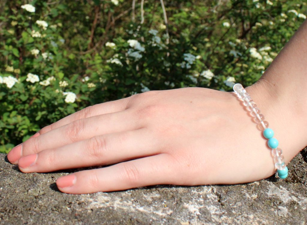 Female hand on rock wearing gemstone bracelet to raise vibrations and heal